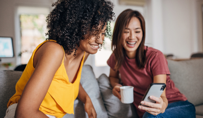 Two friends drinking coffee and looking at a phone